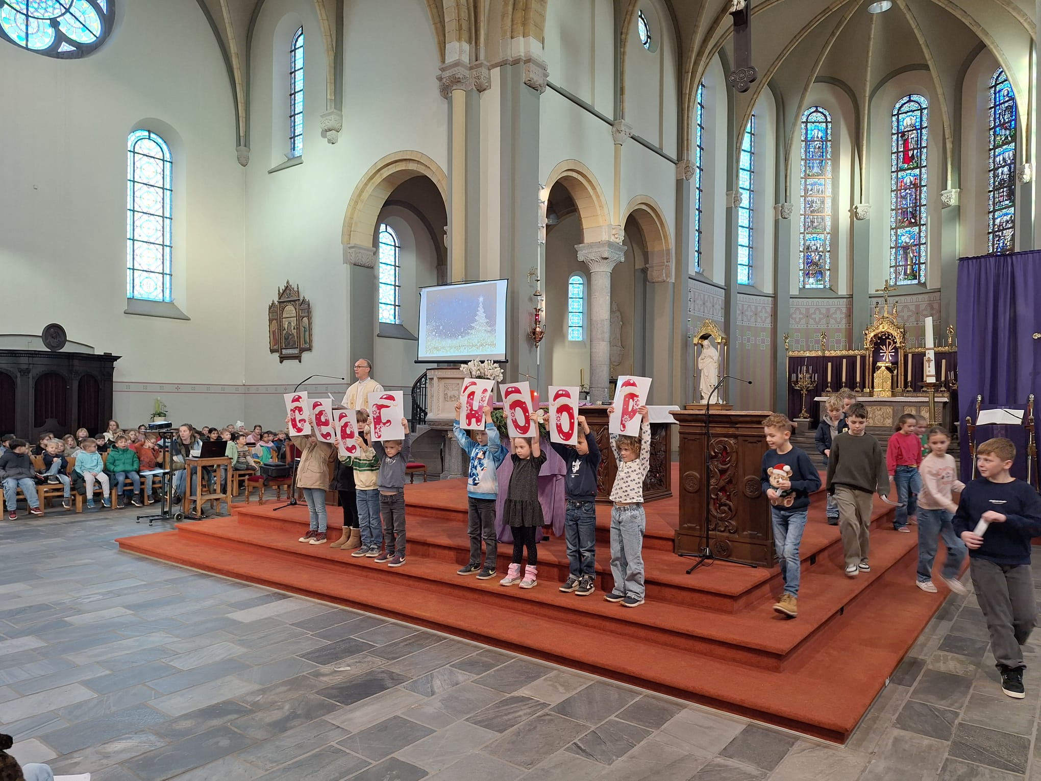 Kinderen houden de letters van 'Geef hoop' omhoog vooraan de kerk. 